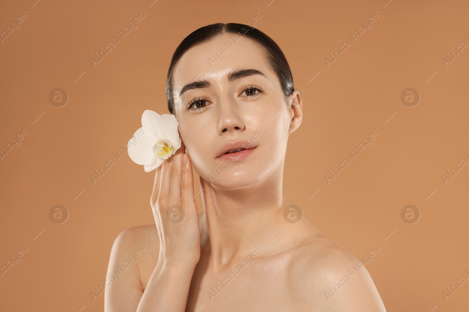 Beautiful woman after spa treatment with orchid flower on beige background Photo of Beautiful woman after spa treatment with orchid flower on beige background