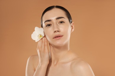 Photo of Beautiful woman after spa treatment with orchid flower on beige background