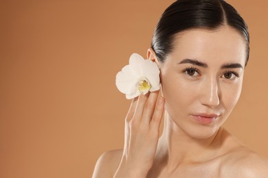 Photo of Beautiful woman after spa treatment with orchid flower on beige background, closeup. Space for text