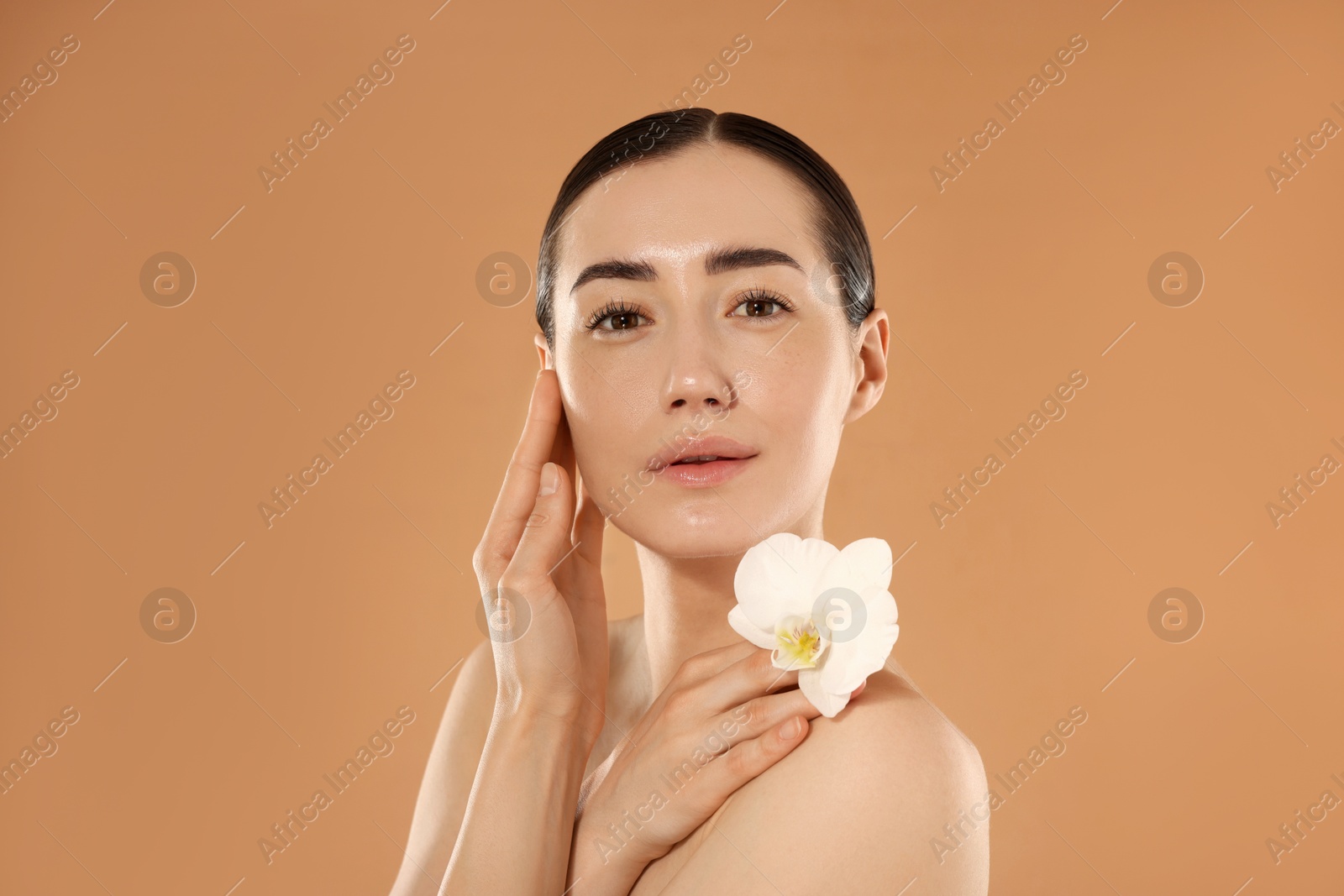 Beautiful woman after spa treatment with orchid flower on beige background Photo of Beautiful woman after spa treatment with orchid flower on beige background