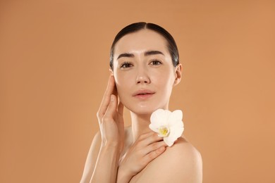 Photo of Beautiful woman after spa treatment with orchid flower on beige background