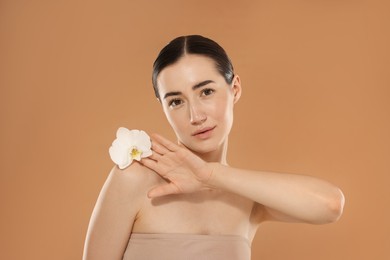 Photo of Beautiful woman after spa treatment with orchid flower on beige background