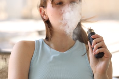Photo of Young woman using electronic smoking device outdoors, closeup