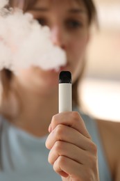 Photo of Young woman using electronic smoking device outdoors, selective focus