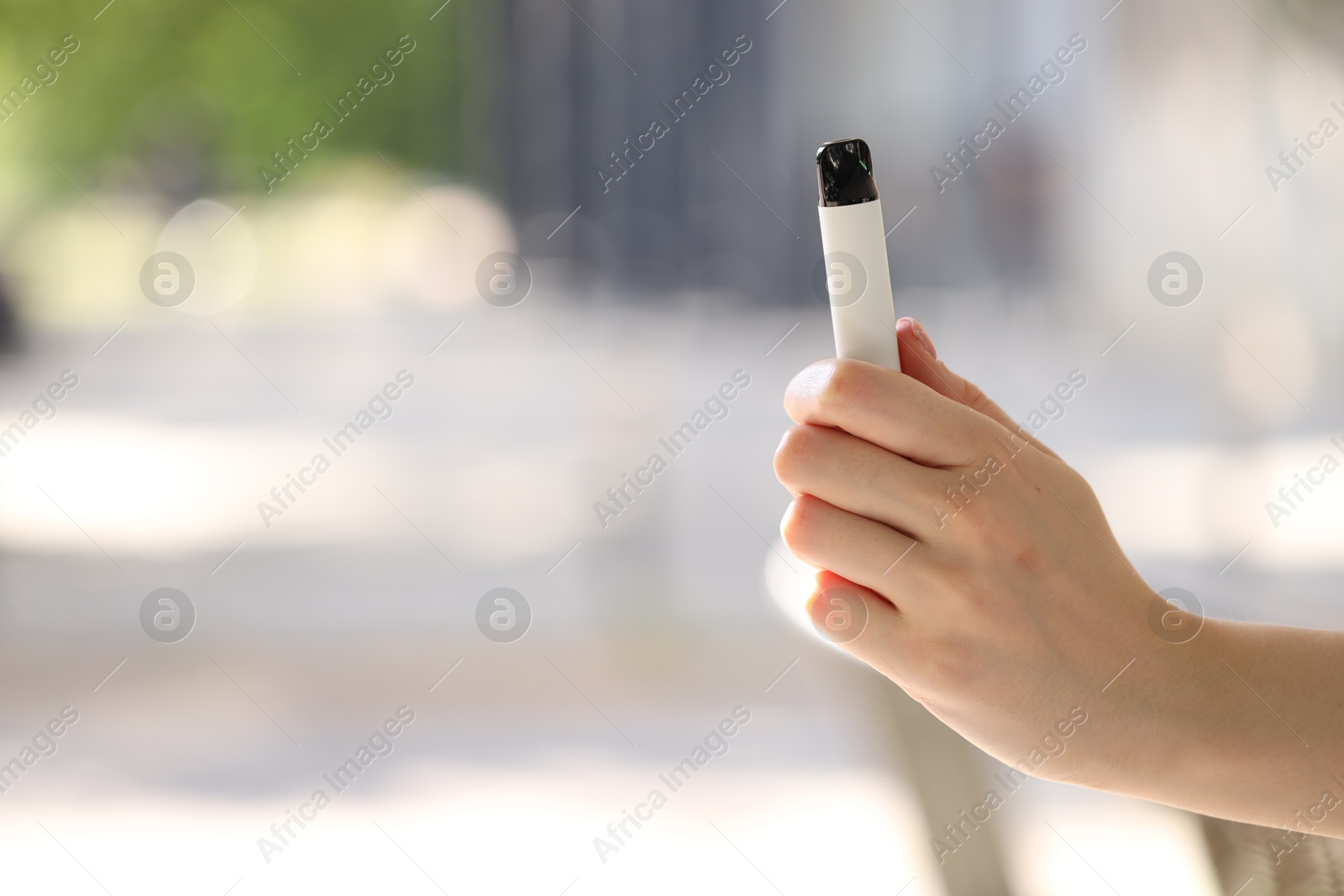 Young woman with electronic smoking device outdoors, closeup. Space for text Photo of Young woman with electronic smoking device outdoors, closeup. Space for text