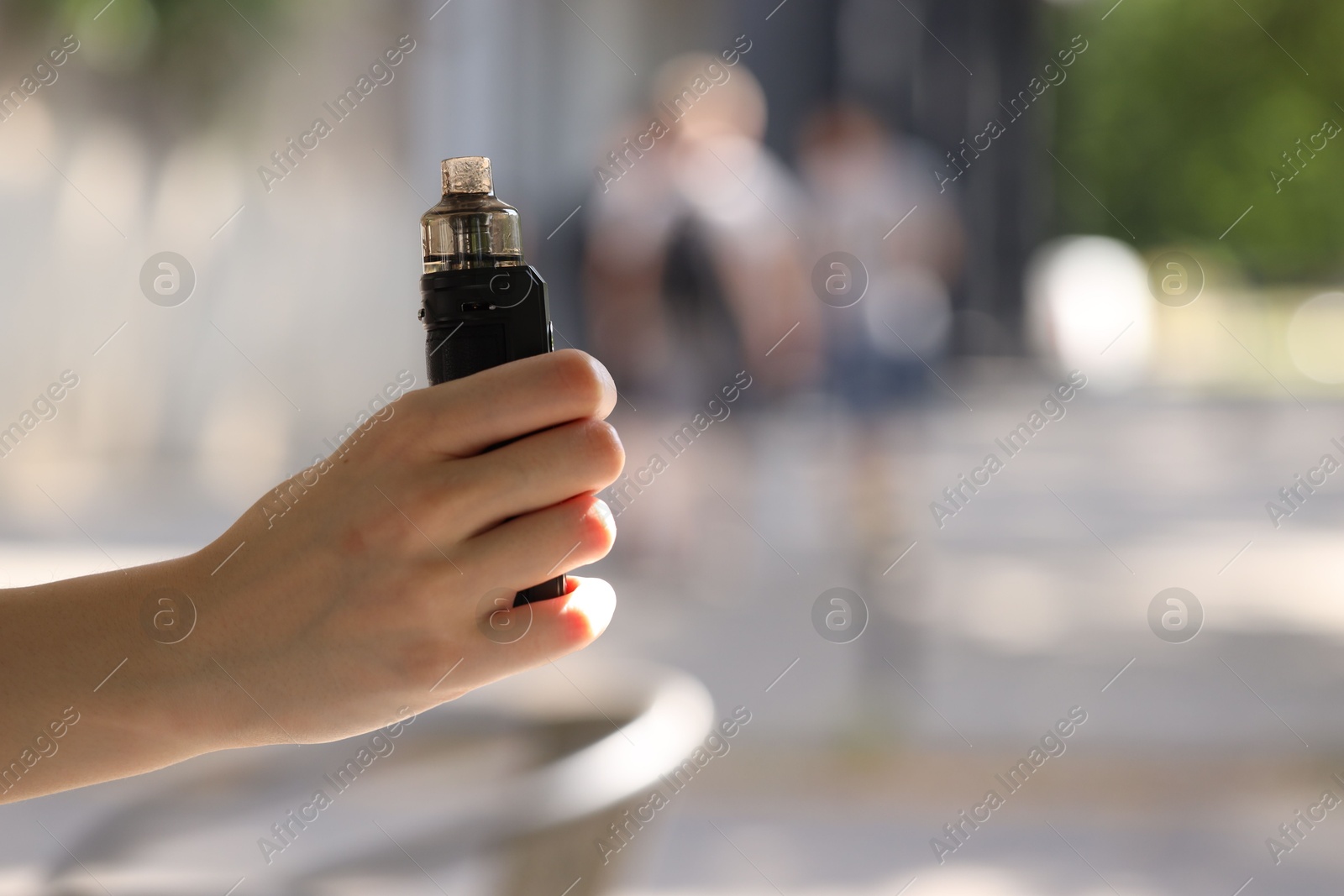 Young woman with electronic smoking device outdoors, closeup. Space for text Photo of Young woman with electronic smoking device outdoors, closeup. Space for text