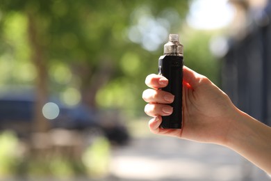 Photo of Young woman with electronic smoking device outdoors, closeup. Space for text