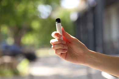 Photo of Young woman with electronic smoking device outdoors, closeup. Space for text