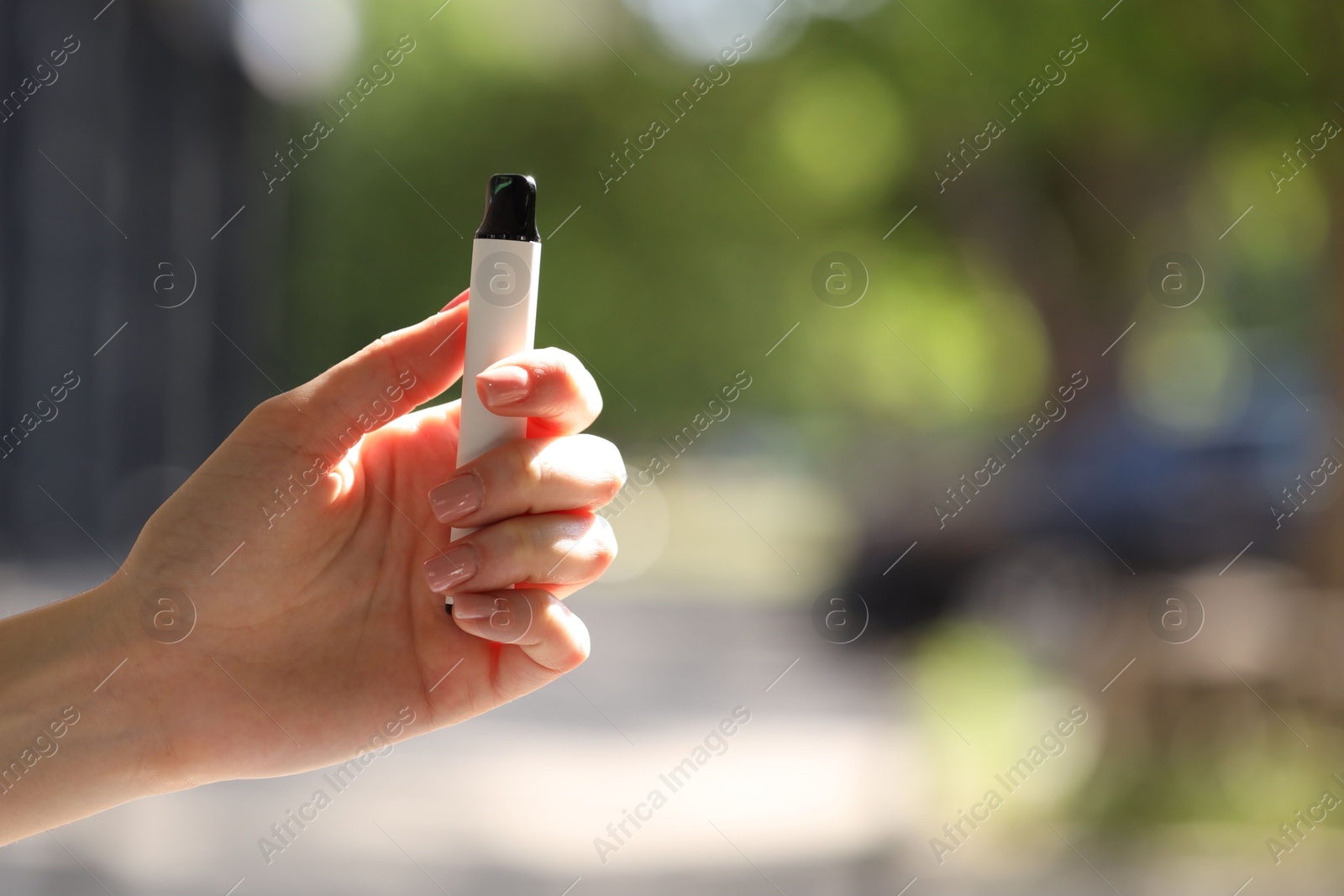 Young woman with electronic smoking device outdoors, closeup. Space for text Photo of Young woman with electronic smoking device outdoors, closeup. Space for text