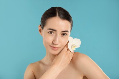 Photo of Portrait of beautiful woman with orchid flower after spa treatment on light blue background