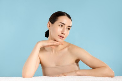 Photo of Beautiful woman with towel after spa treatment on light blue background
