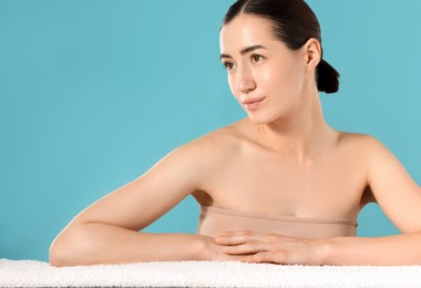 Photo of Beautiful woman with towel after spa treatment on light blue background