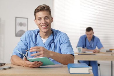 Photo of Medical students in uniforms studying at desks indoors, selective focus