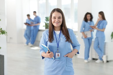Photo of Medical student in uniform with notebook indoors, selective focus