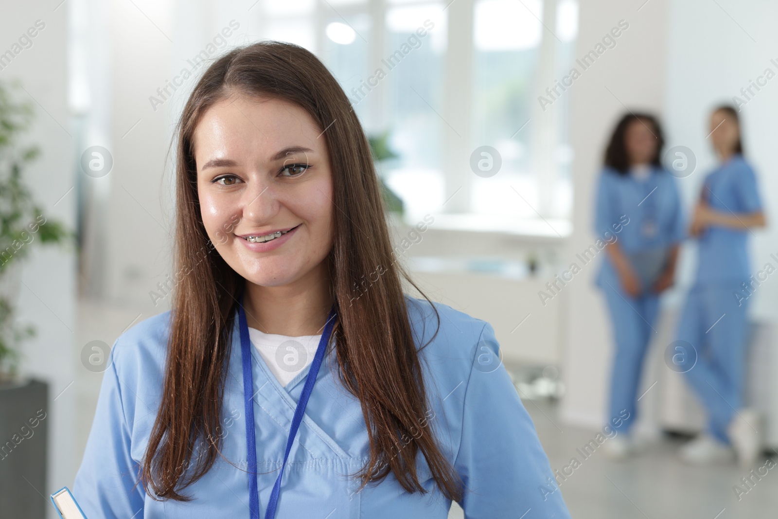 Medical student in uniform with notebook indoors, selective focus Photo of Medical student in uniform with notebook indoors, selective focus