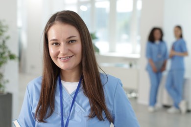 Photo of Medical student in uniform with notebook indoors, selective focus
