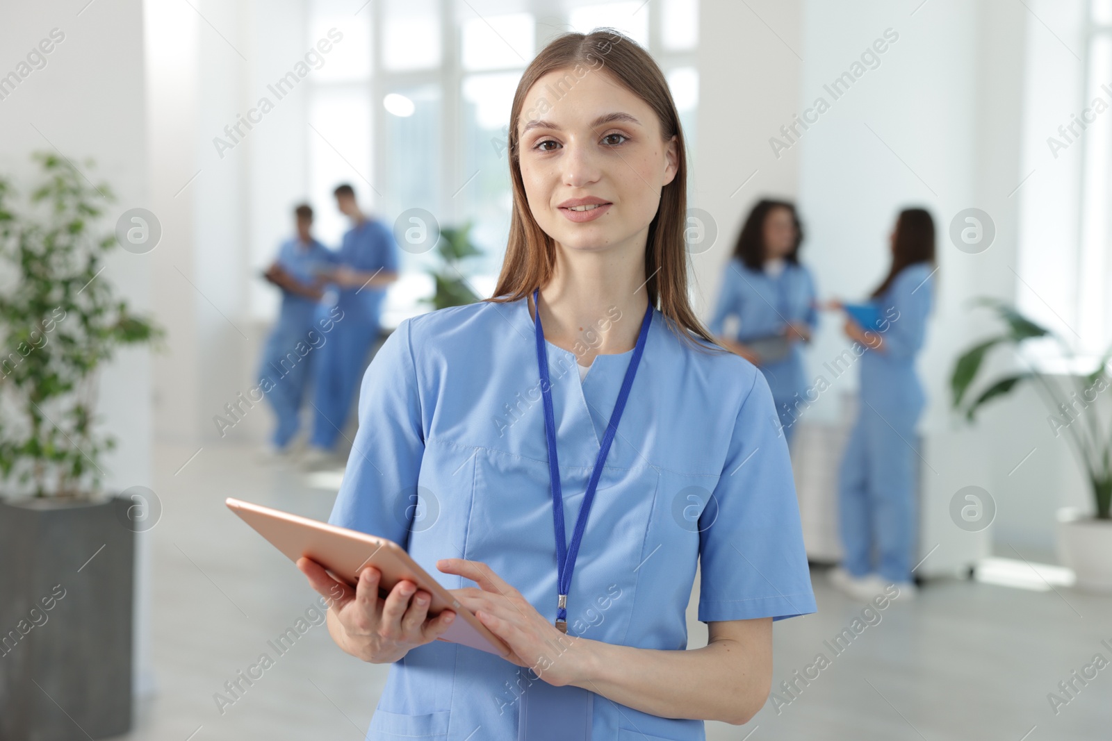 Medical student in uniform with tablet indoors, selective focus Photo of Medical student in uniform with tablet indoors, selective focus