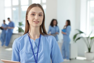 Photo of Medical student in uniform with tablet indoors, selective focus