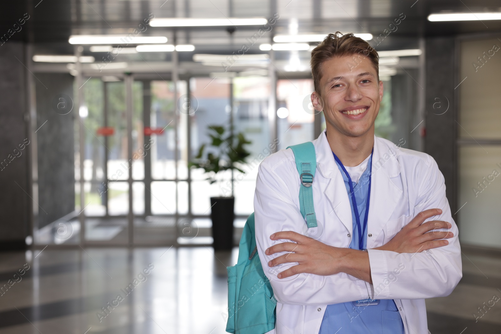 Medical student in uniform with backpack indoors, space for text Photo of Medical student in uniform with backpack indoors, space for text