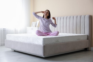 Photo of Woman stretching on bed with orthopedic mattress at home