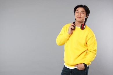 Photo of Handsome Asian man with headphones on grey background. Space for text