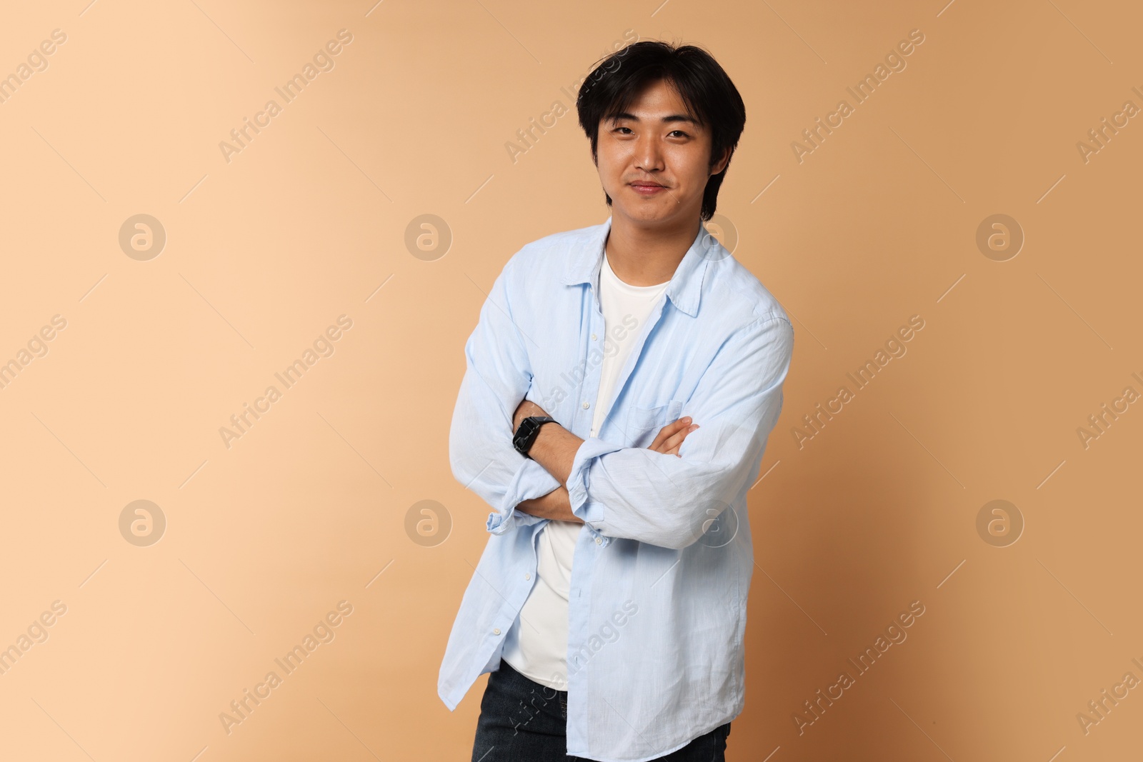 Portrait of handsome Asian man with crossed arms on beige background. Space for text Photo of Portrait of handsome Asian man with crossed arms on beige background. Space for text