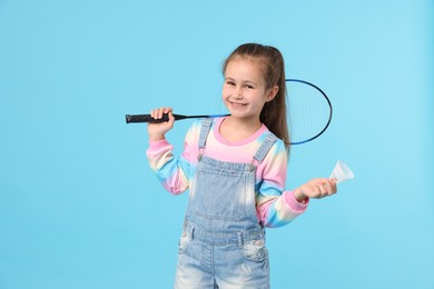 Photo of Little girl with tennis racket and shuttlecock on light blue background