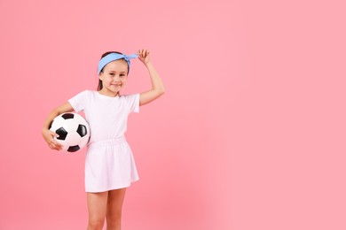 Photo of Little girl with soccer ball on pink background, space for text