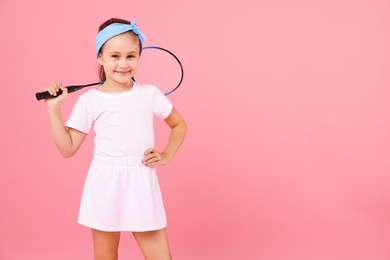Photo of Little girl with tennis racket on pink background, space for text
