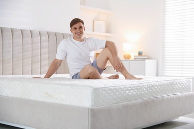 Photo of Young man sitting on bed with soft mattress at home