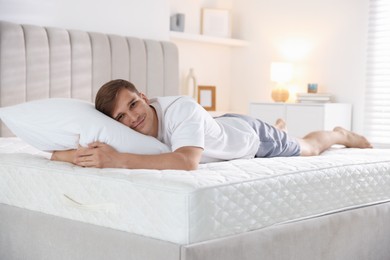 Photo of Young man lying on bed with soft mattress at home