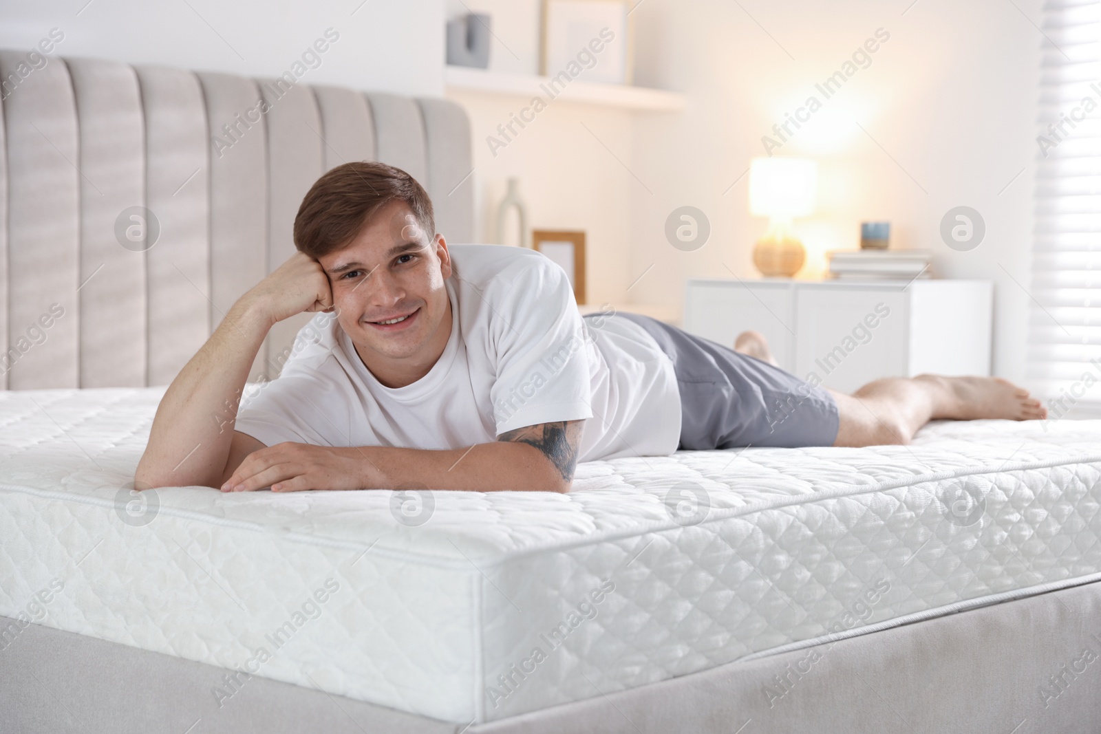 Young man lying on bed with soft mattress at home Photo of Young man lying on bed with soft mattress at home