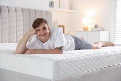 Photo of Young man lying on bed with soft mattress at home