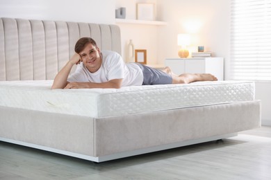 Photo of Young man lying on bed with soft mattress at home