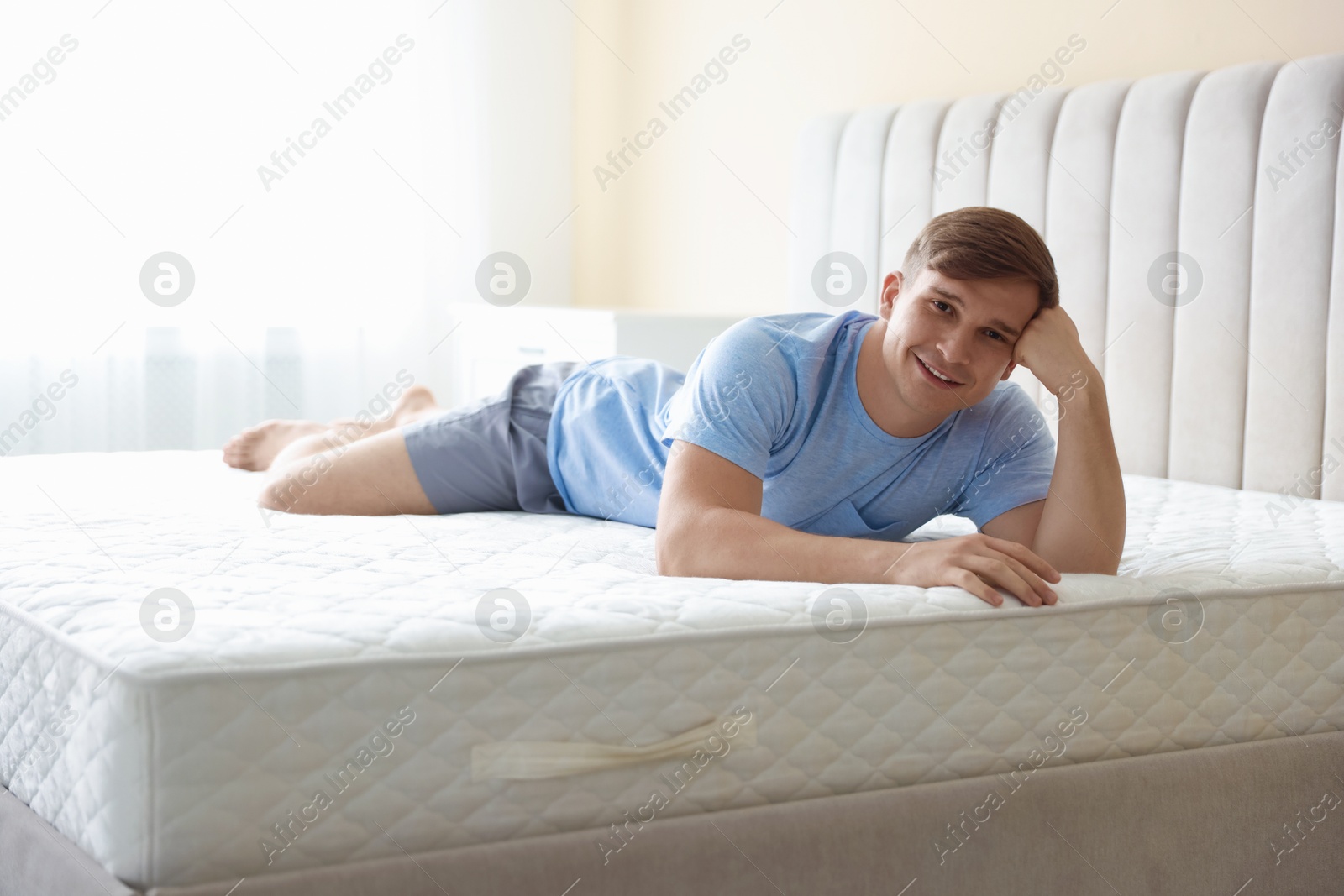 Young man lying on bed with soft mattress at home Photo of Young man lying on bed with soft mattress at home