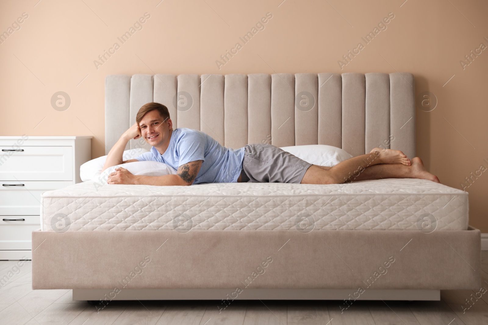 Young man lying on bed with soft mattress at home Photo of Young man lying on bed with soft mattress at home
