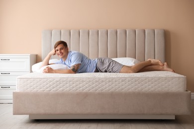 Photo of Young man lying on bed with soft mattress at home