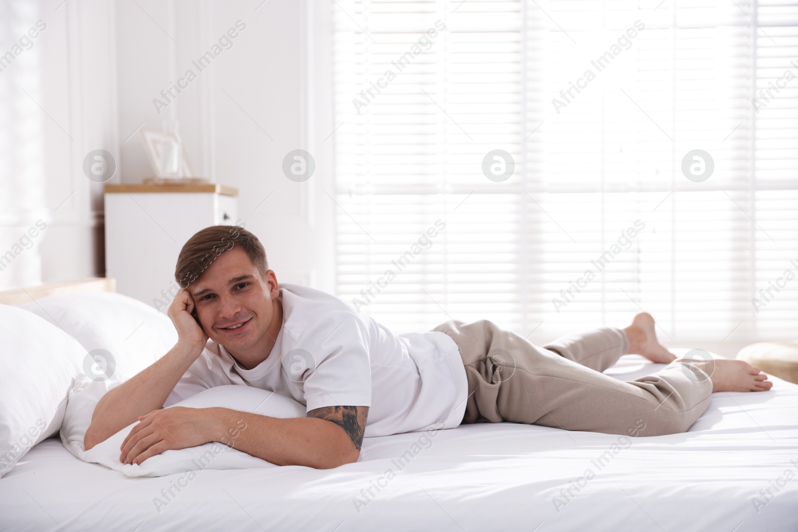 Young man lying on bed with soft mattress at home Photo of Young man lying on bed with soft mattress at home