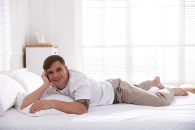 Photo of Young man lying on bed with soft mattress at home