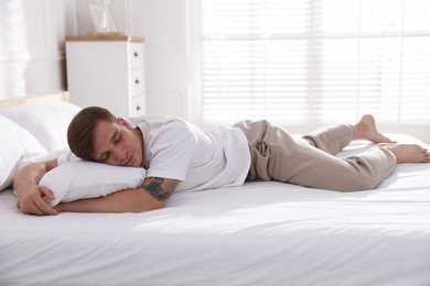 Photo of Young man sleeping on bed with soft mattress at home