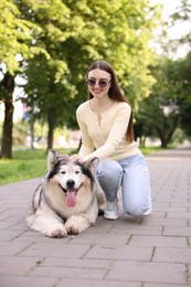 Photo of Happy woman with her cute Alaskan malamute dog in park
