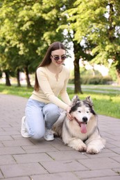 Photo of Happy woman with her cute Alaskan malamute dog in park