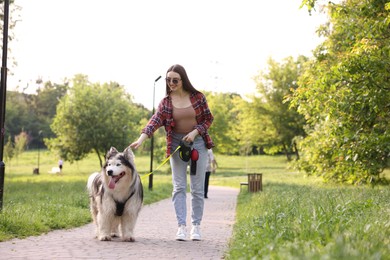 Photo of Happy woman walking with her cute Alaskan malamute dog in park
