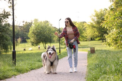 Photo of Happy woman walking with her cute Alaskan malamute dog in park