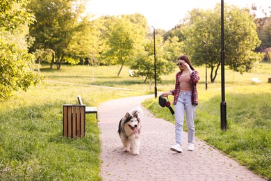 Photo of Happy woman walking with her cute Alaskan malamute dog in park at morning