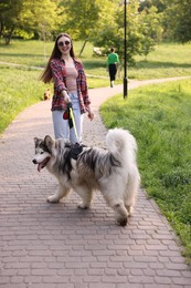 Photo of Happy woman with her cute Alaskan malamute dog in park