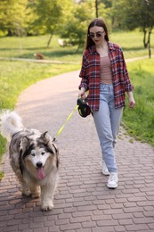 Photo of Woman walking with her cute Alaskan malamute dog in park