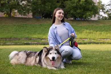 Photo of Happy woman with her cute Alaskan malamute dog on green grass outdoors