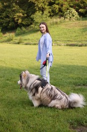 Photo of Happy woman with her cute Alaskan malamute dog on green grass outdoors