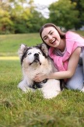 Photo of Happy woman with her cute Alaskan malamute dog on green grass outdoors